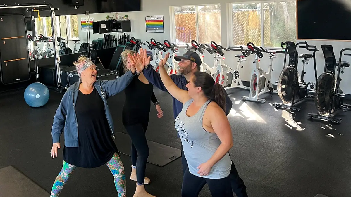 Members celebrating with a group high-five after a HealthSPORT class