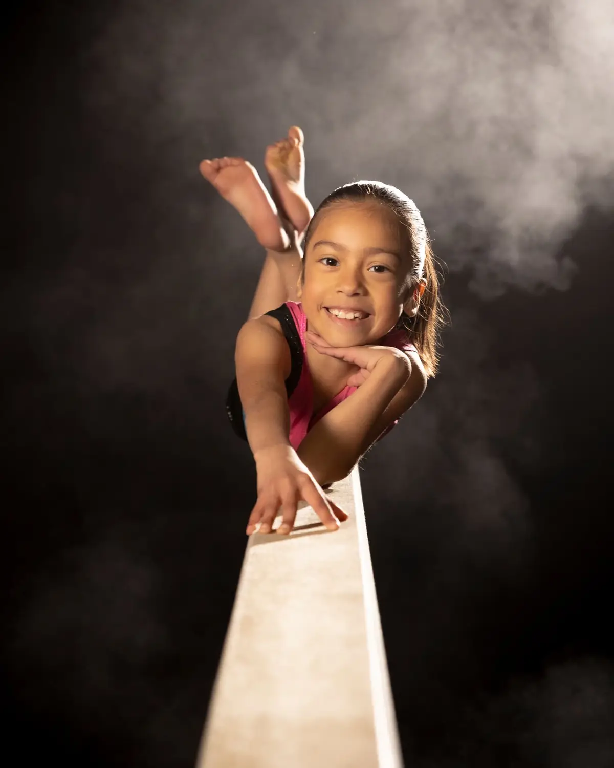 Young gymnast balanced on the beam under a spotlight