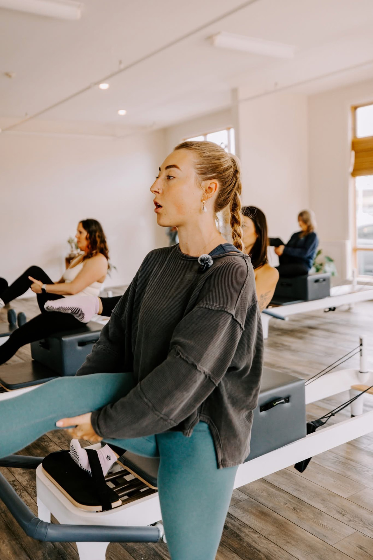 An HS Align instructor demonstrating a standing stretch beside a Reformer during class