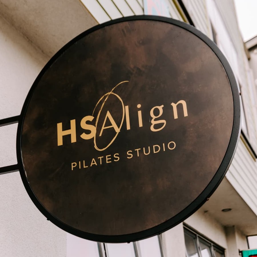 The round HS Align Pilates Studio sign hanging outside the studio