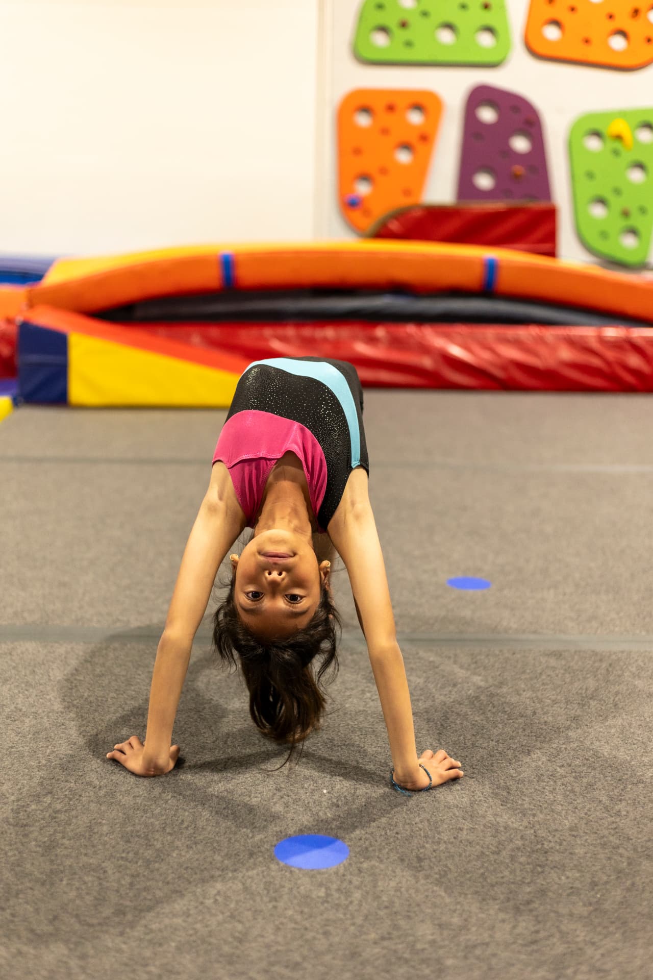 Gymnast pressing into a bridge on the gym floor