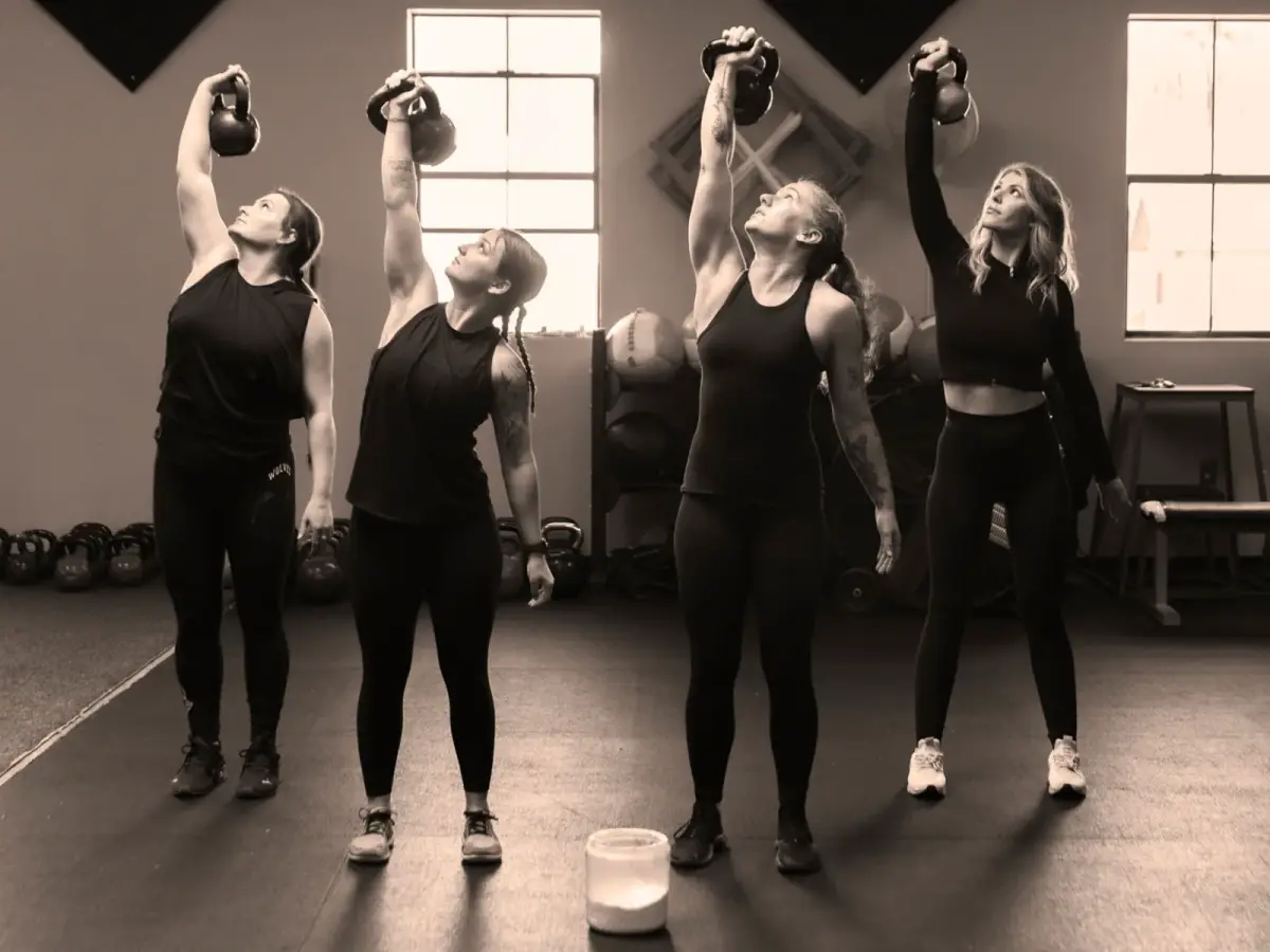 Athletes pressing kettlebells overhead in a HealthSPORT strength session