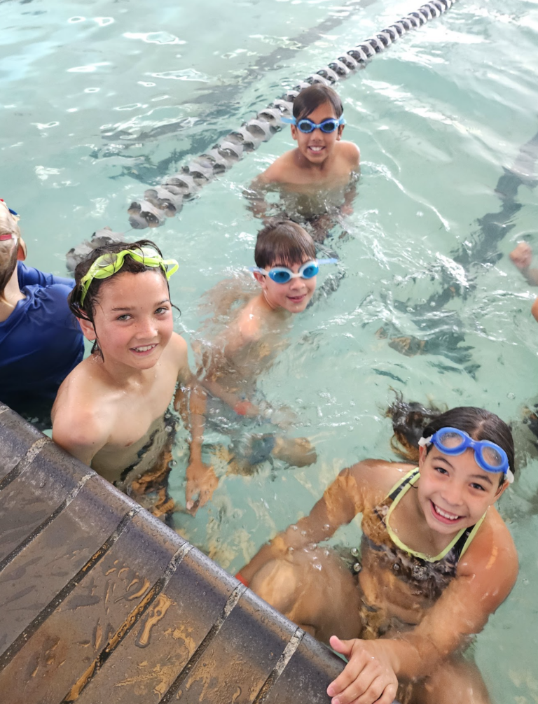 Swimmers in goggles laughing during a HealthSPORT pool party