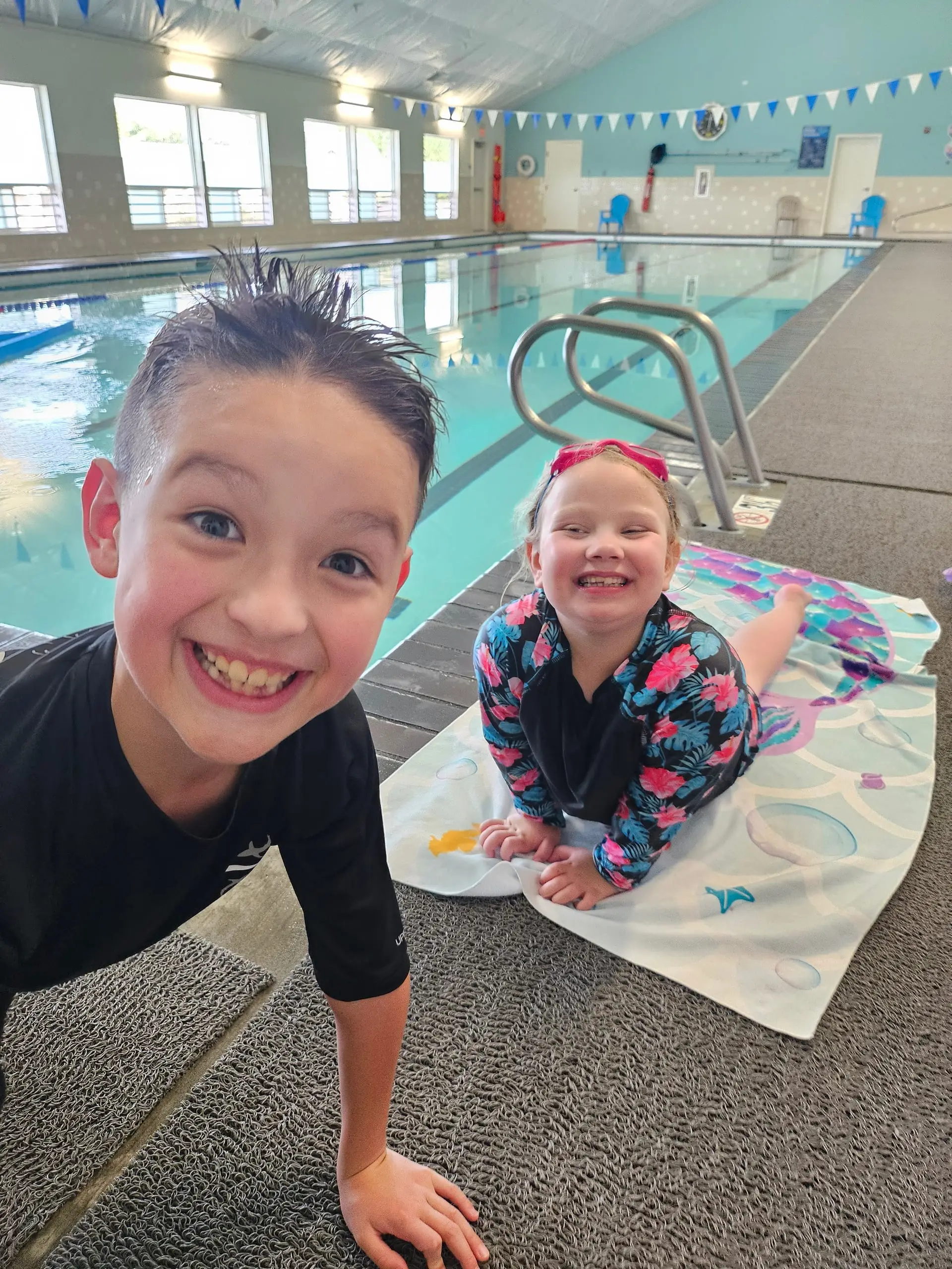 Two young swimmers smiling on the Arcata pool deck