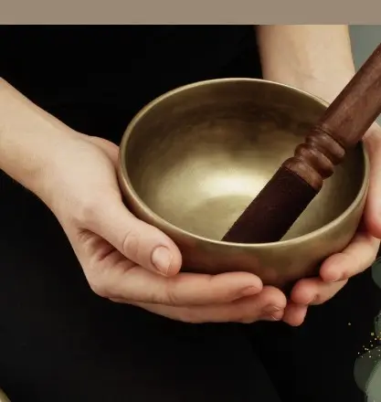 Hands cradling a bronze singing bowl