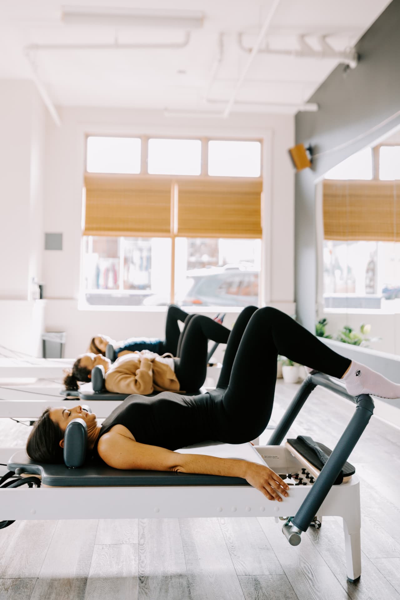 Small group practicing foot work on Pilates reformers in a sunlit HS Align studio